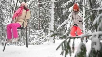 Middle-aged mother and teenage daughter enjoy winter holidays in Finland, swinging together in snowy park. Warm clothes, joyful emotions, family values, seasonal lifestyle and vacation mood. - Powered by Adobe