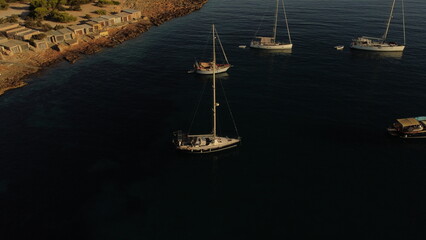 Drone view of boats anchored near rocky coast of Ibiza