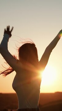 Holiday party. Beautiful girl dancing and having fun with friends at sunset disco. Young smiling woman dancing against sky outdoors. Cheerful woman moving her hands to music at party. Party on beach
