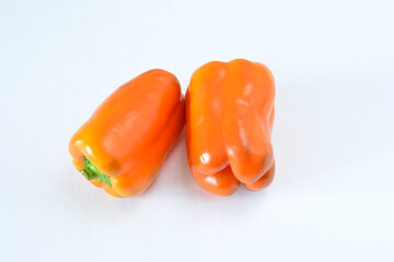 Two vibrant orange bell peppers on a clean white surface cut out