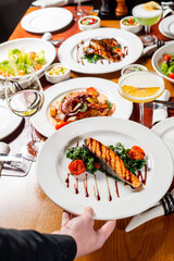 Unrecognizable Waiter serving plate of food in restaurant