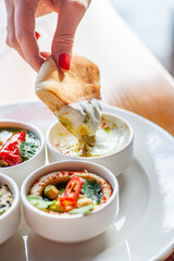 Female hand soaking pita bread in sauce