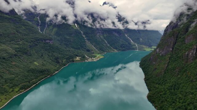 Aerial view of Oldevatnet lake reflecting clouds and surrounded by steep green mountains in Norway