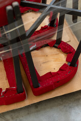 A detail of the upholstery of a chair with red fabric. The concept of artisan production, warehousing, and furniture ready for shipping.