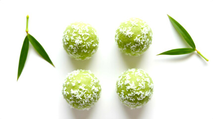 Four green rice balls with coconut flakes and bamboo leaves on a white background. Concept of minimalist Asian dessert presentation with emphasis on naturalness and freshness