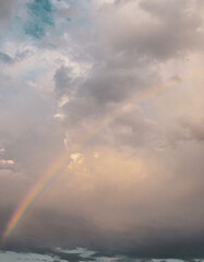 Rainbow arching above gray storm clouds in dramatic cloudy sky