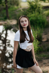 A woman in a white top and a black skirt by the lake