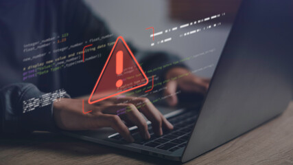Close-up of hands typing on laptop with warning error icon and code overlay, representing data...