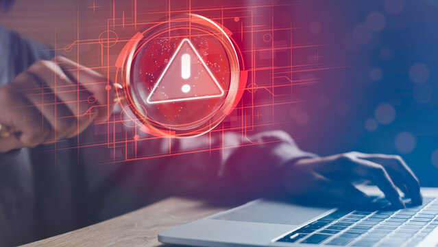 Businessman using laptop with magnifying glass highlighting digital warning icon, symbolizing digital risk, cybersecurity threats, data protection, and online risk management in modern technology.