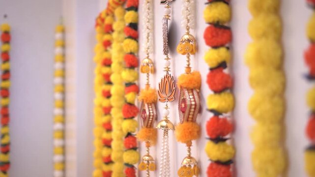 Traditional Indian torans and marigold garlands with bells and pearls, hanging as festive decor for Diwali, Navratri, or a wedding ceremony.