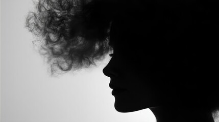Black and white silhouette of a woman's face. the woman's head is facing towards the right side of the image, with her hair blowing in the wind.