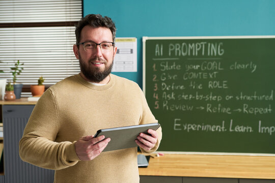 Teacher holding a tablet in front of a chalkboard with AI prompting tips