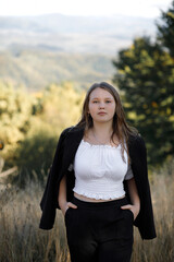 A woman in a black pantsuit against the backdrop of autumn mountains