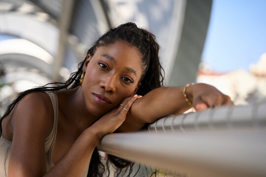 Young woman leaning on railing in urban setting contemplating