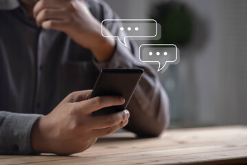 Person using smartphone with chat bubble icons, online messaging, mobile communication, social media chat, instant messaging, customer support, chatbot conversation, digital communication technology.