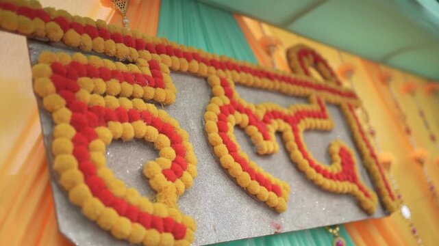 Close-up of a traditional "Haldi" sign in Hindi, made of marigold flowers, decorating an Indian wedding pre-wedding ceremony backdrop
