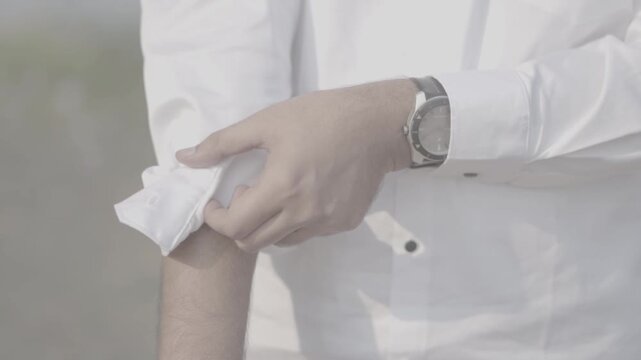 Close-up: Man in a white shirt rolling up his sleeves, getting ready for work or action.