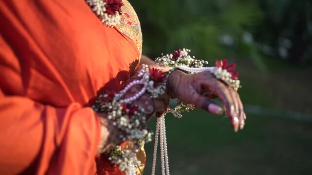 Traditional Indian Wedding, Bridal Floral and Pearl Jewelry Detail on Bride's Hands during Pre-Wedding Ceremony or haldi ceremony
