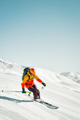 Male adult skier carving turn on freshly groomed slope in snowy mountain resort during sunny winter...