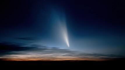 Photograph of a comet streaking across the night sky. the comet is in the center of the image, with a bright blue light emanating from the center.