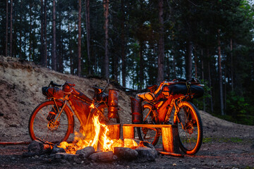 Two bicycles with bags sit near a fire at night