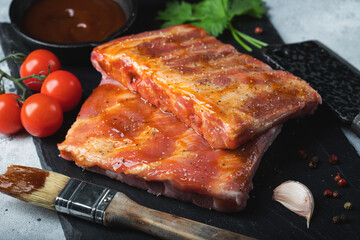 Ready for BBQ raw pork spare ribs with barbecue sauce. Black background. Top view