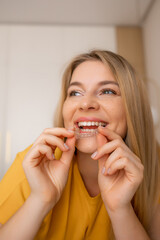 Woman smiling while inserting clear dental aligner into her mouth