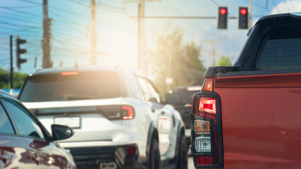 Rear side of pickup car orange color. Turn on brake light. Traffic congestion of red light control in the junction. with tropical weather conditions in Thailand.