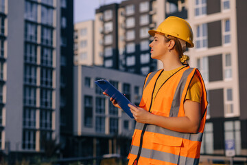 Construction site manager analyzing building projects wearing safety gear and helmet outdoors