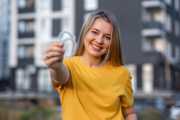 Smiling woman holding a dental aligner in an urban outdoor setting