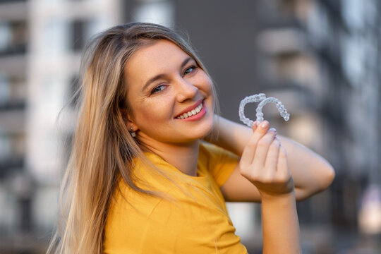 Woman smiling with clear aligners in outdoor urban background