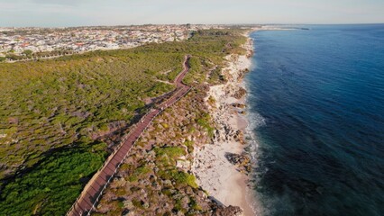 Two adults engage in exercise along serene coastal path. Ocean waves and natural scenery create a...