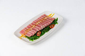 fish fillet cut into slices in a plate with chukka on a white background