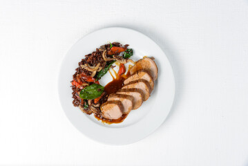 brown rice with mushrooms, vegetables and meat in a white plate on a white background