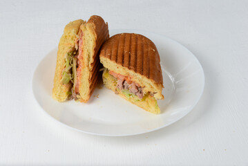 Grilled sandwich with meat and vegetables on a white plate
