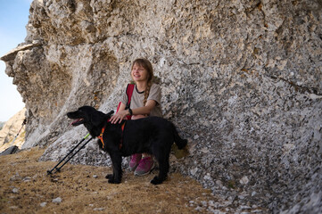 Woman Relaxing During a Hike with Her Black Dog in a Natural Setting