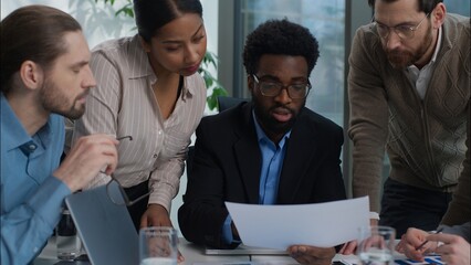 African American leader listen colleagues employers team in office Caucasian Indian business men women analysing document paperwork together businesspeople discussion multiethnic workers planning work