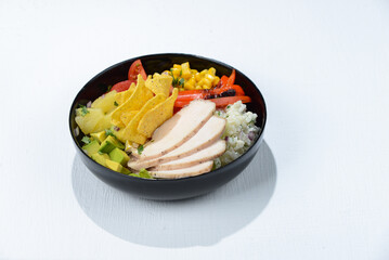 Chicken taco bowl in a black plate with chili pepper and herbs on a white background