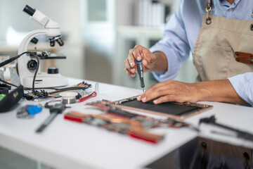 Technician repairing electronic device using screwdriver in laboratory