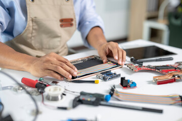 Technician repairing electronic device using multimeter and soldering iron