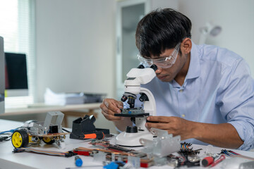 Engineer analyzing electronic components with microscope in robotics laboratory