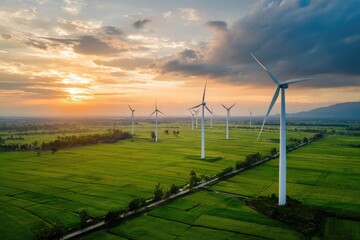 Aerial view of wind turbines in a green field at sunset generating renewable energy.