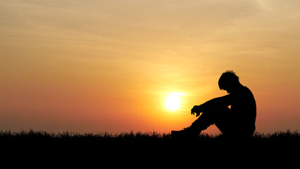 Solitude at Sunset: A solitary figure sits silhouetted against a vibrant sunset, evoking feelings...