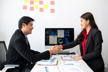 Business partners shaking hands after agreeing to work together in modern office