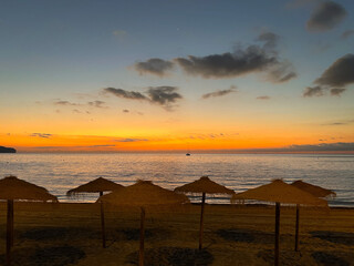 Sunset at sea. Sunset at sea. Straw beach umbrellas. Photo