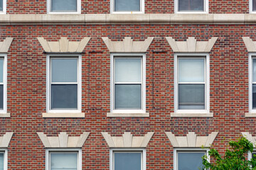 Obraz premium Classic red brick facade with orderly windows revealing timeless urban residential architecture in Cambridge, Massachusetts, USA 
