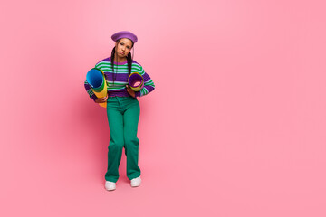 Young woman with striped sweater and pink background posing with colorful rolled paper materials in a fun and stylish setting