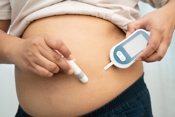 Asian woman injecting herself diabetes injecting insulin in stomach at home.