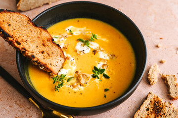 Kürbissuppe mit gerösteten Brot in einer schwarzen Schüssel. Herbst, Mittagessen.