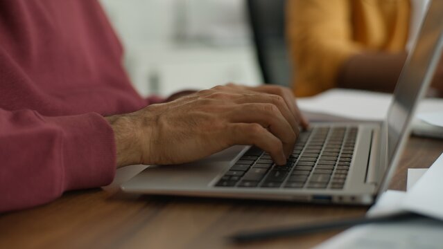 Close up unrecognizable business man typing laptop working computer process creative modern coworking unrecognizable informal team meeting startup partners international people briefing brainstorming